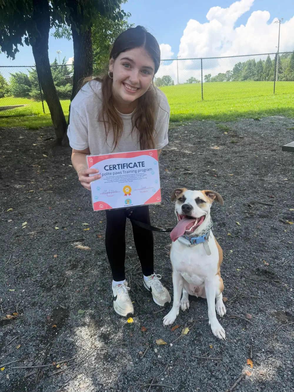 Georgia Pet Pal trainer crouching beside a dog with its training certificate